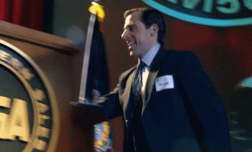 A Man In A Suit And Tie Holds A Trophy In Front Of A Podium With The Word Cia On It GIF