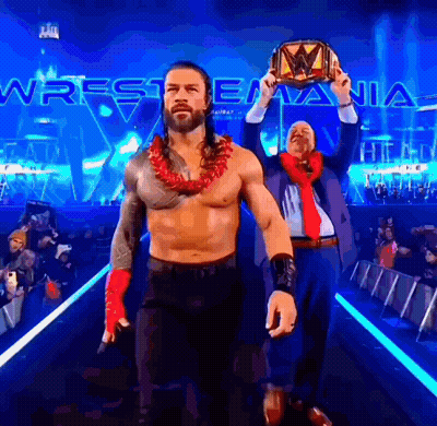A Man In A Suit And Tie Holds A Wrestling Championship Belt GIF