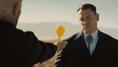 A Man In A Suit And Tie Holds A Yellow Object In His Hand GIF