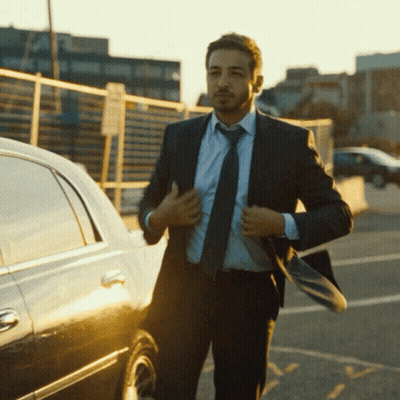 A Man In A Suit And Tie Is Adjusting His Jacket GIF