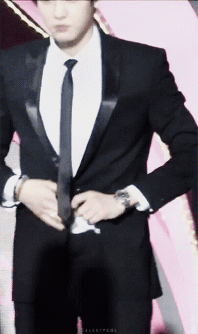 A Man In A Suit And Tie Is Adjusting His Suit Jacket GIF