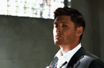 a man in a suit and tie is adjusting his tie in a room .