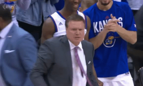 A Man In A Suit And Tie Is Applauding A Basketball Player Wearing A Kansas Shirt GIF