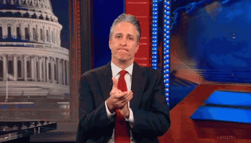 A Man In A Suit And Tie Is Applauding In Front Of A Capitol Building GIF