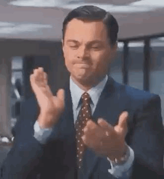 A Man In A Suit And Tie Is Applauding . GIF