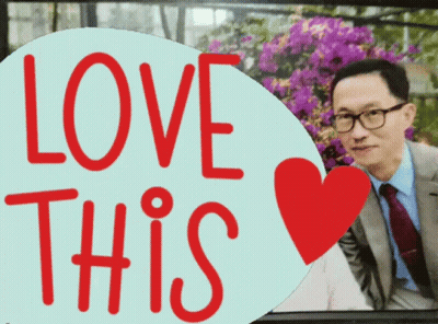 A Man In A Suit And Tie Is Behind A Sign That Says " Love This " GIF