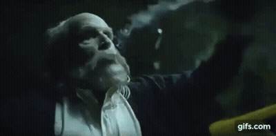 A Man In A Suit And Tie Is Blowing A Cloud Of Smoke Out Of His Mouth . GIF