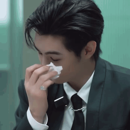A Man In A Suit And Tie Is Blowing His Nose With A Napkin GIF