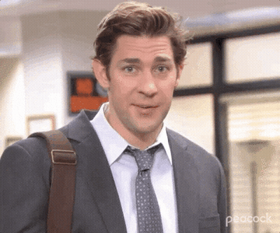 A Man In A Suit And Tie Is Carrying A Bag . GIF