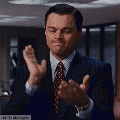 A Man In A Suit And Tie Is Clapping His Hands And Making A Face . GIF