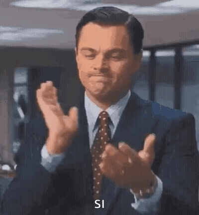 A Man In A Suit And Tie Is Clapping His Hands And Saying `` Si '' . GIF