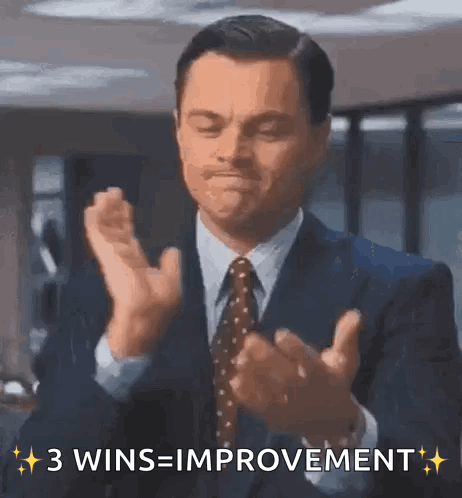 A Man In A Suit And Tie Is Clapping His Hands And Says 3 Wins = Improvement GIF