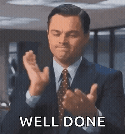 A Man In A Suit And Tie Is Clapping His Hands With The Words `` Well Done '' Written Below Him . GIF