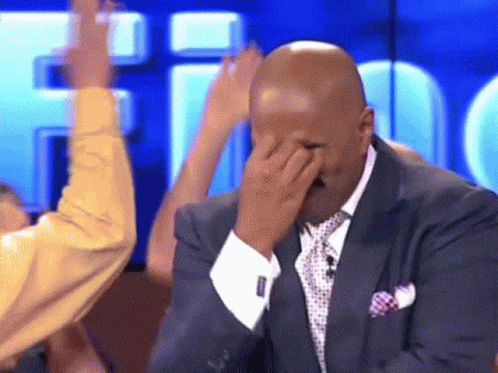 A Man In A Suit And Tie Is Covering His Face GIF