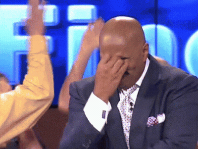A Man In A Suit And Tie Is Covering His Face GIF
