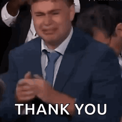A Man In A Suit And Tie Is Crying In A Crowd And Saying Thank You . GIF