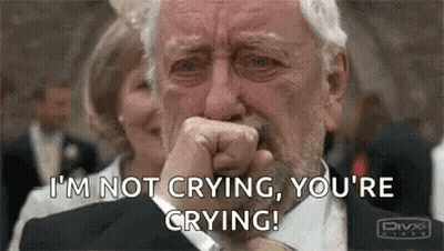 A Man In A Suit And Tie Is Crying While Covering His Mouth With His Hand . GIF