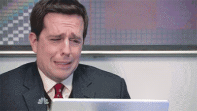 a man in a suit and tie is crying while sitting in front of a laptop .