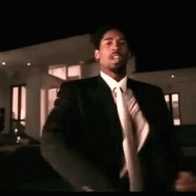 A Man In A Suit And Tie Is Dancing . GIF