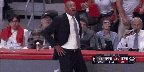 A Man In A Suit And Tie Is Dancing During A Basketball Game GIF