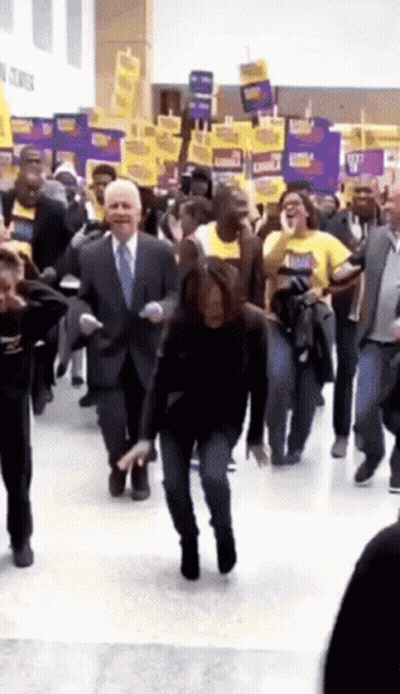 A Man In A Suit And Tie Is Dancing In A Crowd GIF