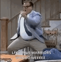 A Man In A Suit And Tie Is Dancing In A Living Room With A Table In The Background . GIF