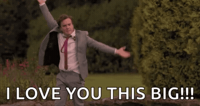 A Man In A Suit And Tie Is Dancing In A Park With His Arms Outstretched . GIF