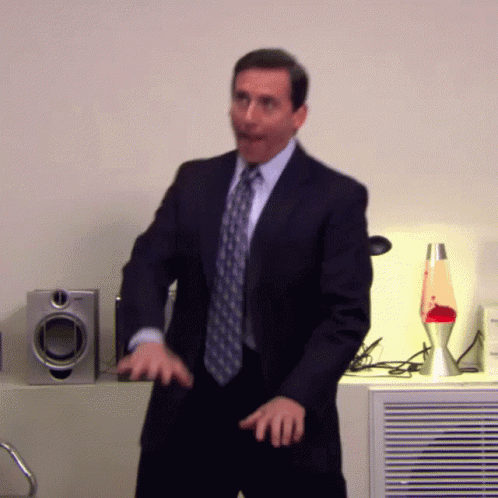 A Man In A Suit And Tie Is Dancing In A Room GIF