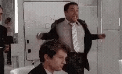 A Man In A Suit And Tie Is Dancing In A Room . GIF