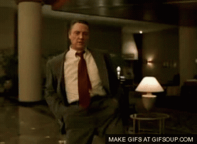 A Man In A Suit And Tie Is Dancing In A Room GIF