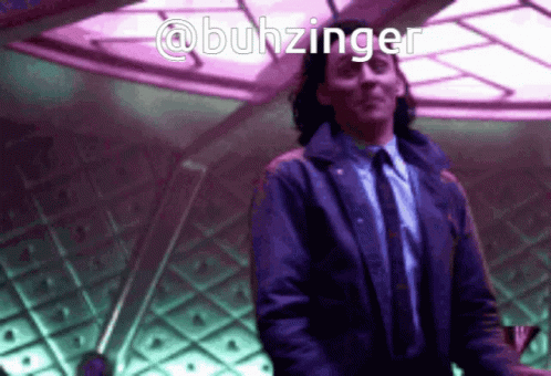 A Man In A Suit And Tie Is Dancing In A Room With The Name @Buhzinger Above Him GIF