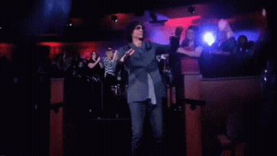 A Man In A Suit And Tie Is Dancing In Front Of A Crowd GIF