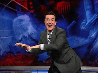 A Man In A Suit And Tie Is Dancing In Front Of A Screen That Says The C GIF