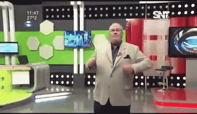 A Man In A Suit And Tie Is Dancing In Front Of A Snf Sign GIF