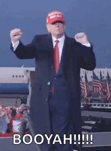A Man In A Suit And Tie Is Dancing In Front Of An Airplane While Wearing A Maga Hat . GIF