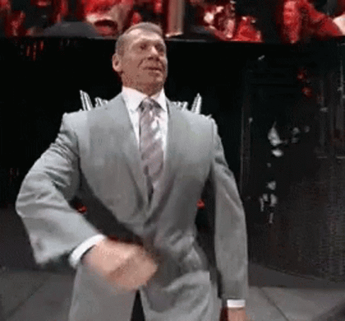 A Man In A Suit And Tie Is Dancing On A Stage In Front Of A Crowd . GIF
