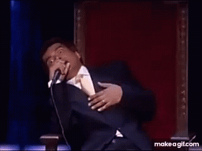 A Man In A Suit And Tie Is Dancing On A Stage In Front Of A Microphone . GIF