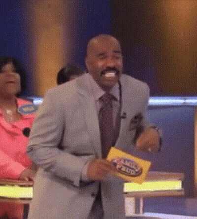 A Man In A Suit And Tie Is Dancing On A Stage While Holding A Yellow Card That Says Family Feud . GIF