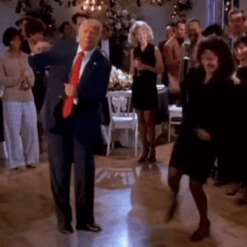 A Man In A Suit And Tie Is Dancing With A Woman GIF