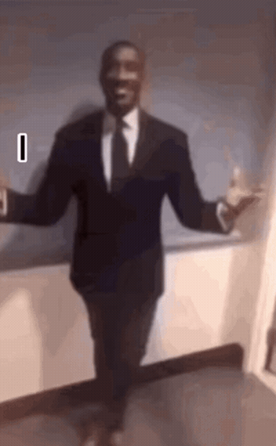 A Man In A Suit And Tie Is Dancing With His Arms Outstretched . GIF