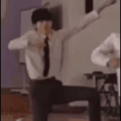 A Man In A Suit And Tie Is Dancing With His Arms Outstretched In A Room . GIF