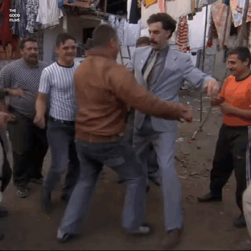 A Man In A Suit And Tie Is Dancing With Other Men GIF