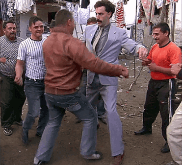 A Man In A Suit And Tie Is Dancing With Other Men GIF