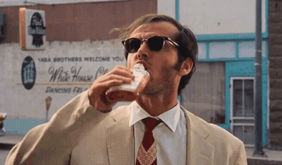 A Man In A Suit And Tie Is Drinking From A Cup In Front Of A White House Restaurant GIF