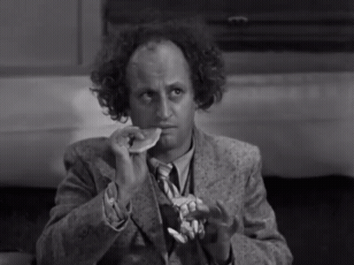 A Man In A Suit And Tie Is Eating A Piece Of Food GIF