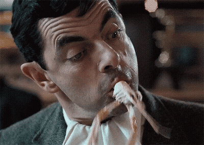 A Man In A Suit And Tie Is Eating A Piece Of Food GIF