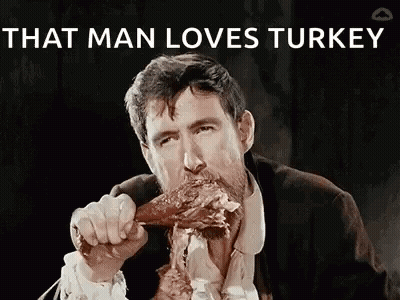 A Man In A Suit And Tie Is Eating A Turkey Leg . GIF
