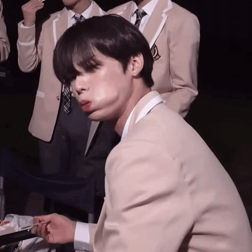 A Man In A Suit And Tie Is Eating Something GIF