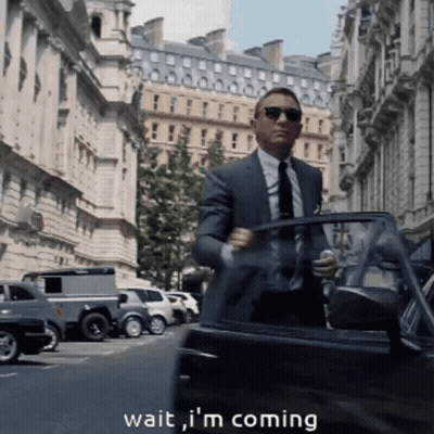 A Man In A Suit And Tie Is Getting Out Of A Car With The Words " Wait I 'M Coming " Below Him GIF