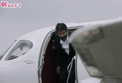 A Man In A Suit And Tie Is Getting Out Of A Private Jet . GIF